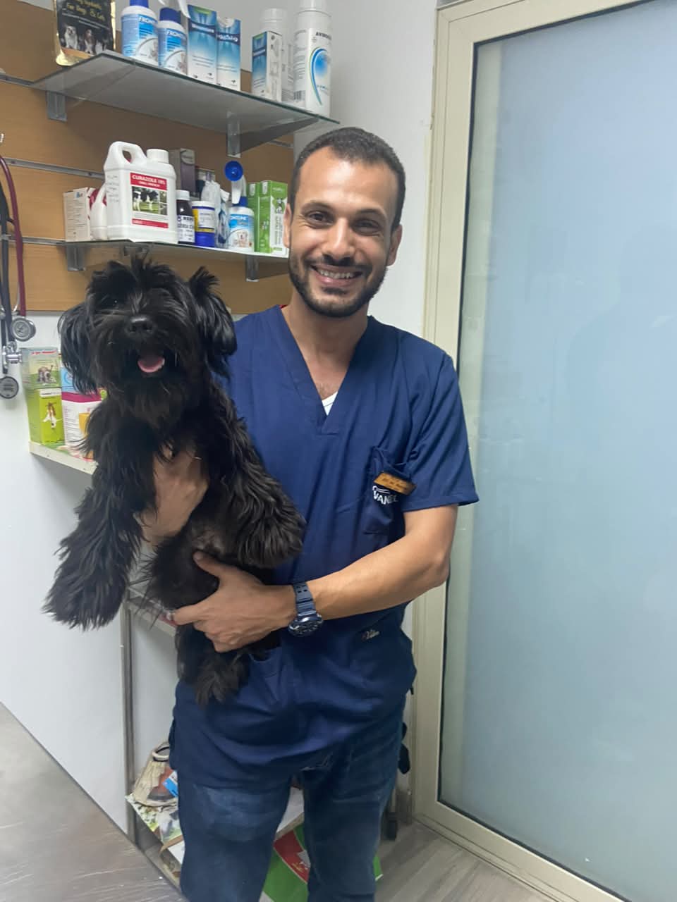طبيب بيطري يحمل كلباً أسود صغيراً بحنان